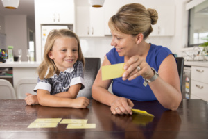 Happy Young Mother And Her Sweet And Beautiful Little Daughter Playing Card Game At Home Kitchen Smiling And Having Fun Together In Education And Family Lifestyle Concept