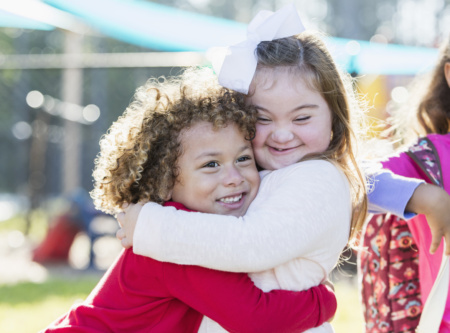 Little Girl With Down Syndrome And Boy Hugging