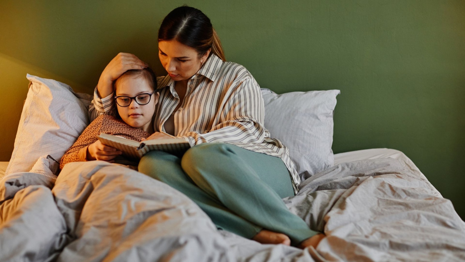 Adult and chold reading in bed together - creating Predictable Daily Routines