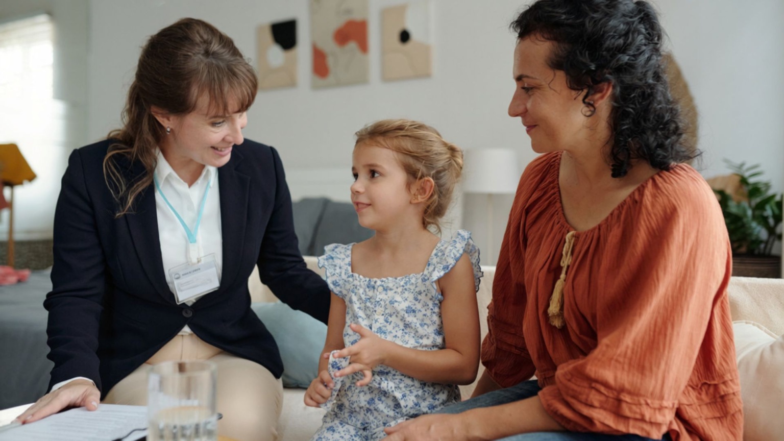 Two adults sitting with a child, one is a support workers and the other a caregiver.