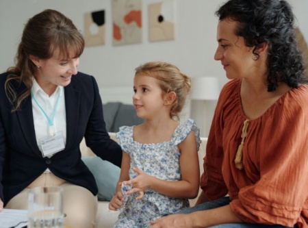 Two adults sitting with a child, one is a support workers and the other a caregiver.